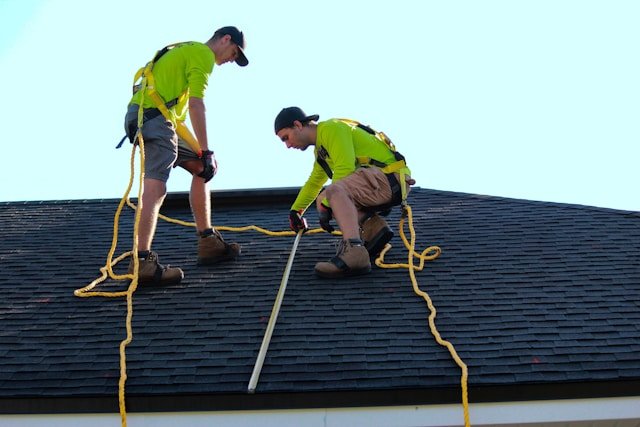 Two roofers on a roof explaining how to generate roofing leads for roofing businesses