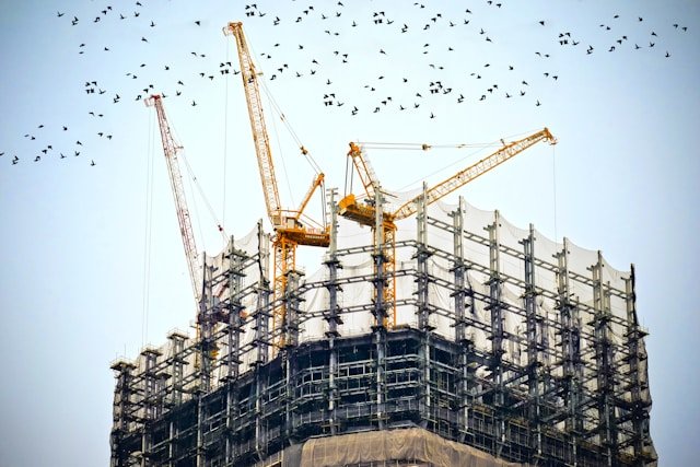 Two cranes on top of a building exemplifying the need for commercial construction lead generation